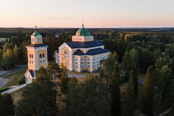 sunset aerial image of big yellow wooden church in Kerimäki