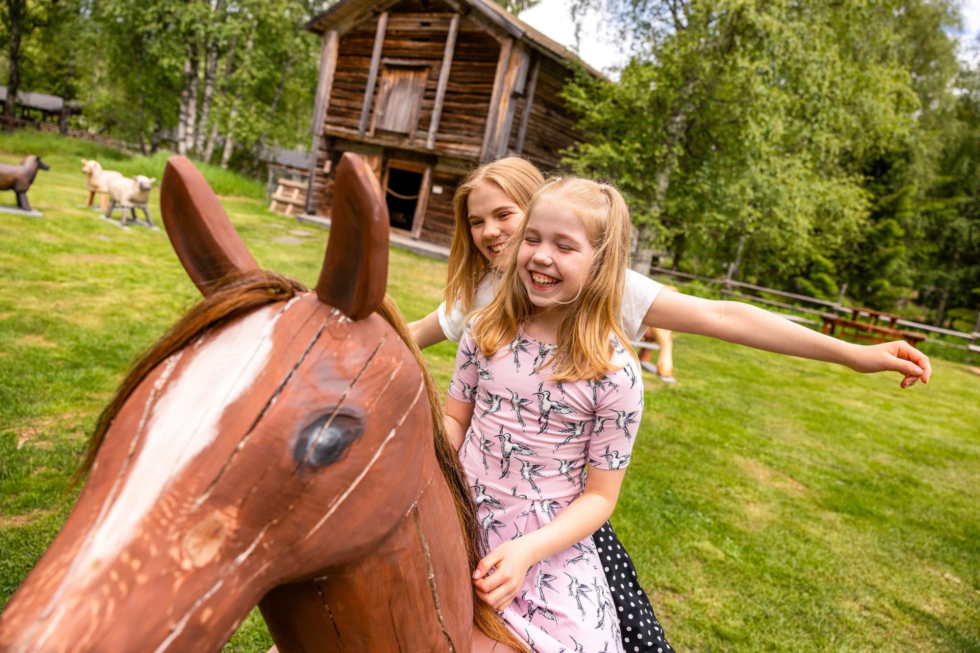 Happy girls riding a wooden horse.