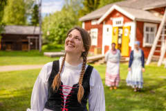 Smiling woman in traditional costume. The farmyard yard in the background .