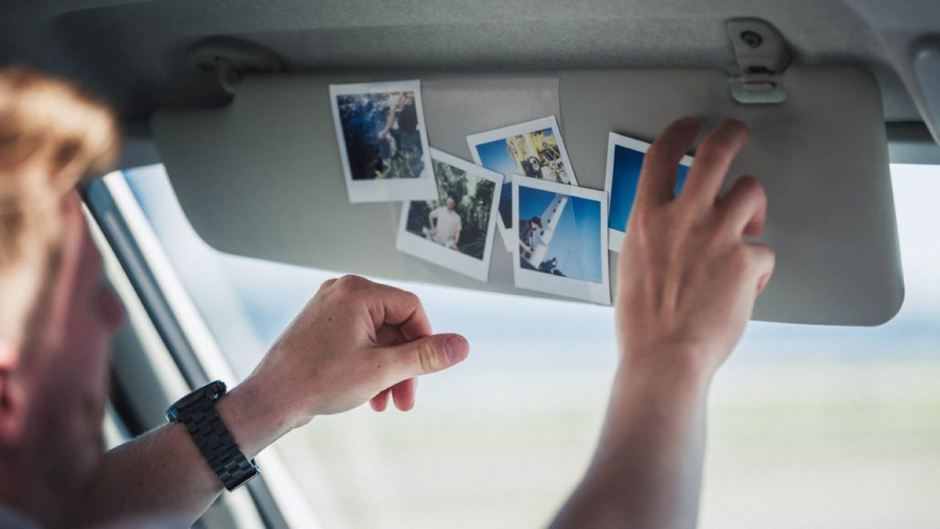 Sun screen of a car with polaroid photos of a summer trip.