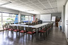 Vaaleassa kokoustilassa on isot ikkunat ja paljon valoa. Valkoiset pöydät ja kaksiväriset puutuolit on kalustettu U-muotoon.