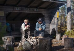 Kaksi retkeilijää istumassa laavulla Pyhä-Luoston kansallispuistossa. Kuva: Teemu Kuisma /Metsähallitus.