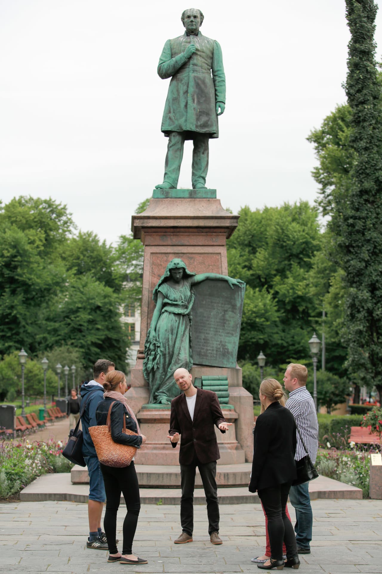 Guide with a group of customers standing in front of a statue in the Esplanade Park.