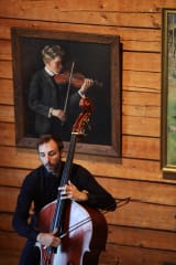A double bassist playing and whistling