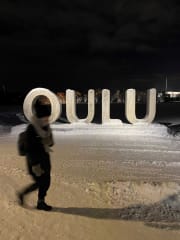 A person in front of big OULU letters.