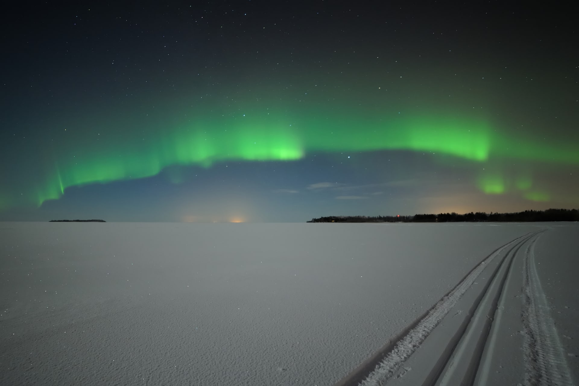 An empty snowy field with an open sky full of northern lights
