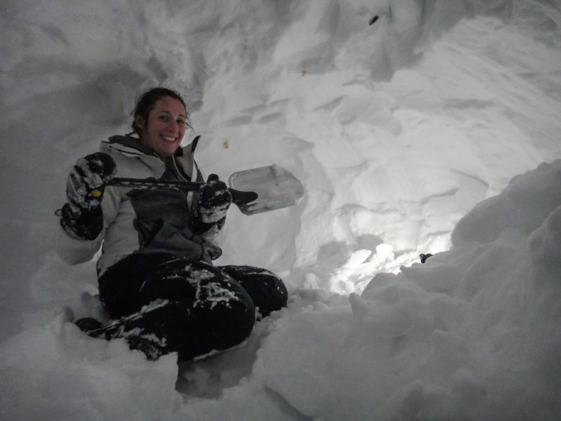 A woman digging snow inside an igloo.