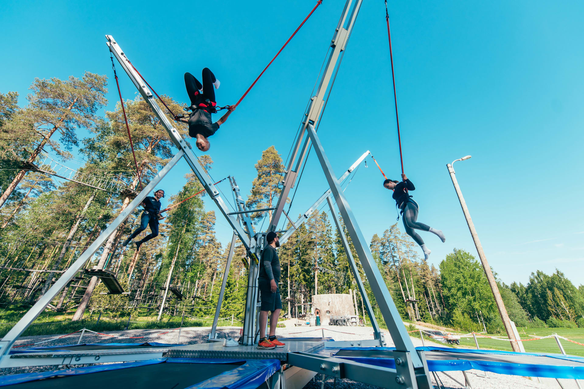 Kaksi naista ja mies pomppivat yhtäaikaa Pajulahden Seikkailupuiston Bungee-tarmpoliinilla