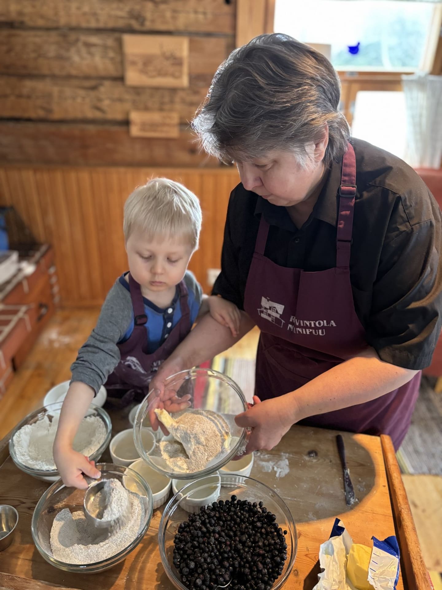 Woman and child are making dough for blueberry-pies.