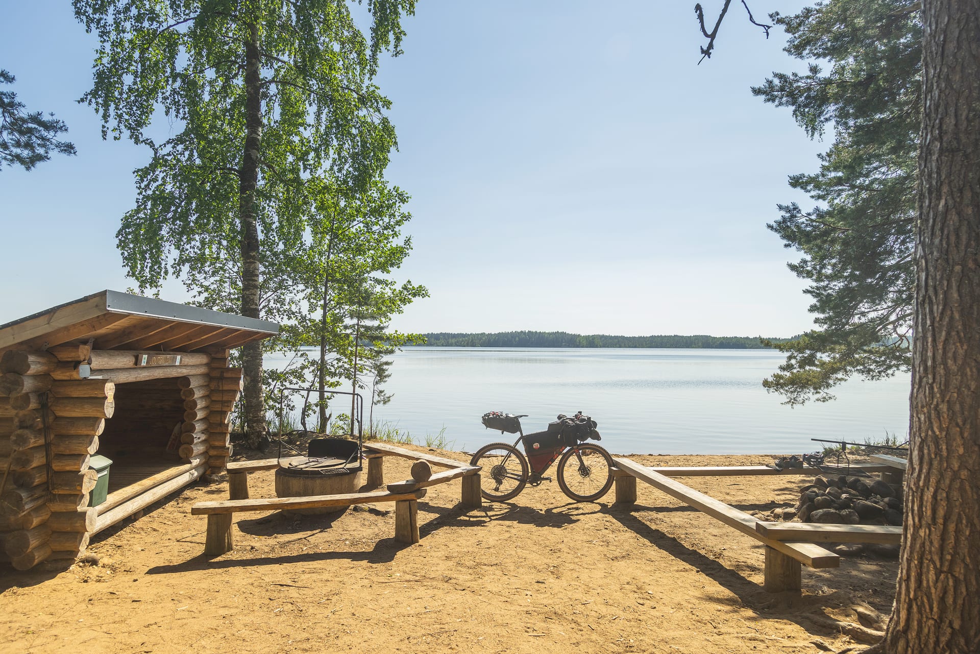 Pyörä seisomassa järven rannalla laavun vieressä.