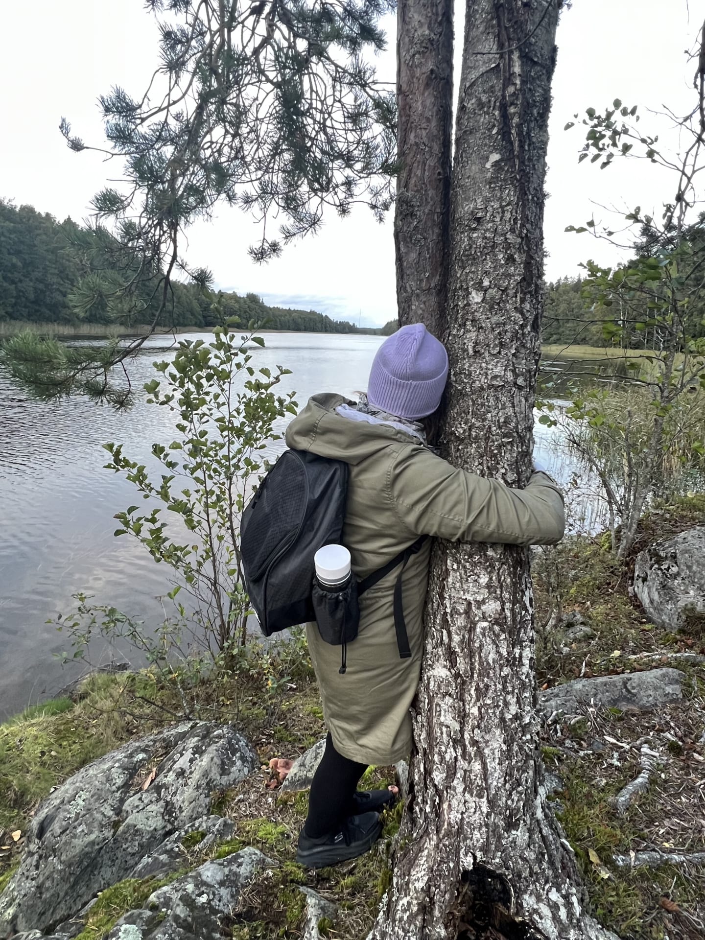 Woman hugging a tree by a Finnish lake