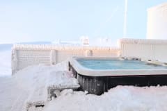 Outdoor hot tub, snow covered fence and sunshine.