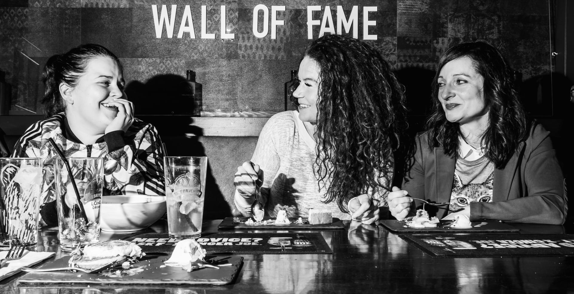 Smiling woman eating in a restaurant under a Wall of Fame sign