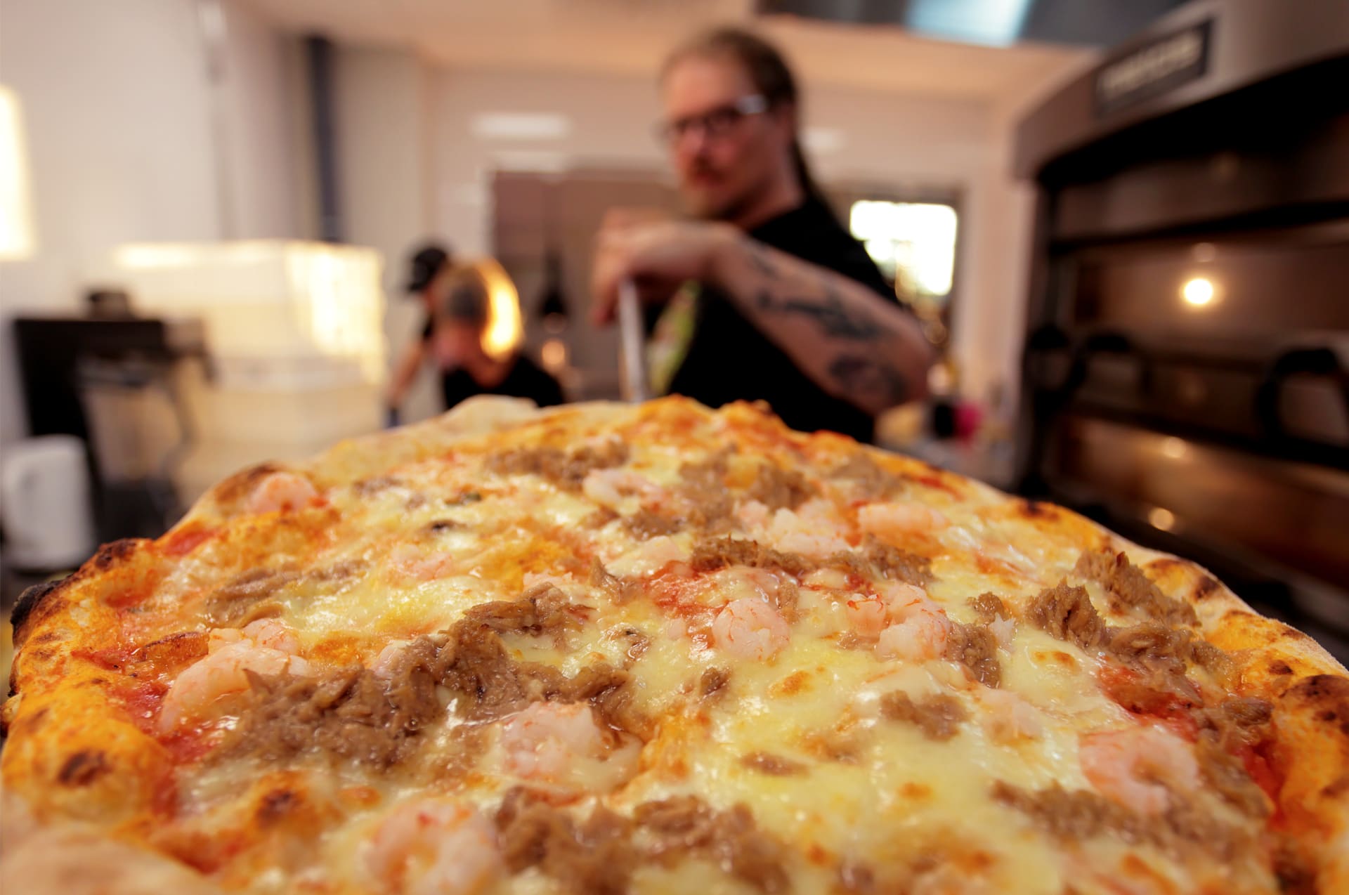 Chef preparing fresh artisan pizza in a professional pizza oven at the brewery
