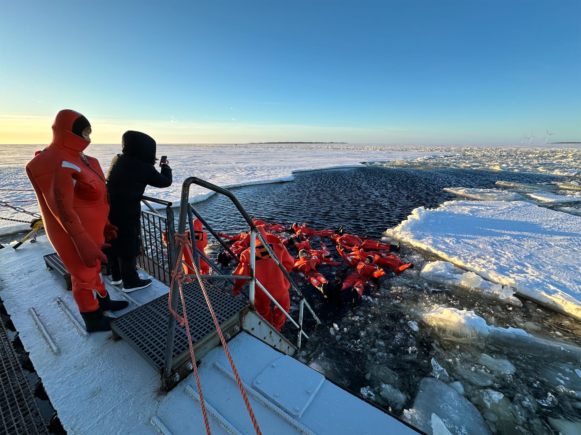 people swimming with survival suits in the frozen sea water