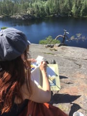 Nainen istuu kalliolla.