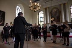 a choir sings in a church lead by a conductor