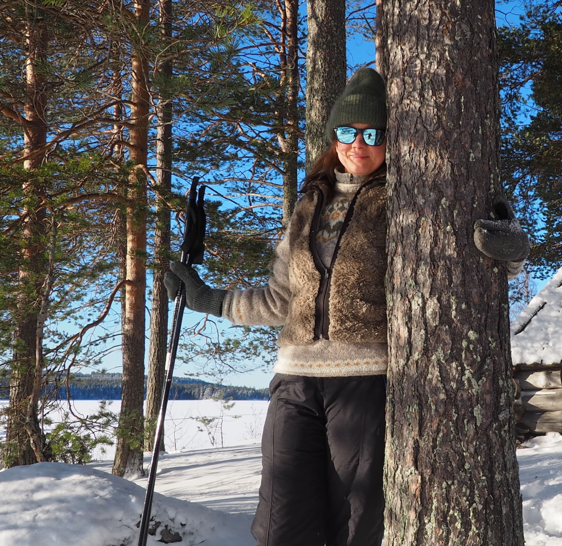 Women leaning on a pine in wintery landscape.