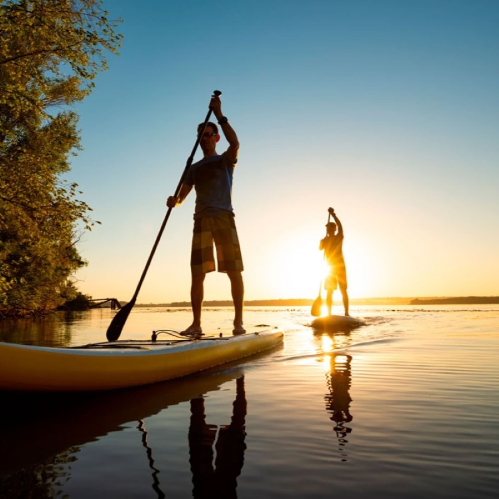 Kaksi SUP-lautailijaa järvellä auringonlaskussa