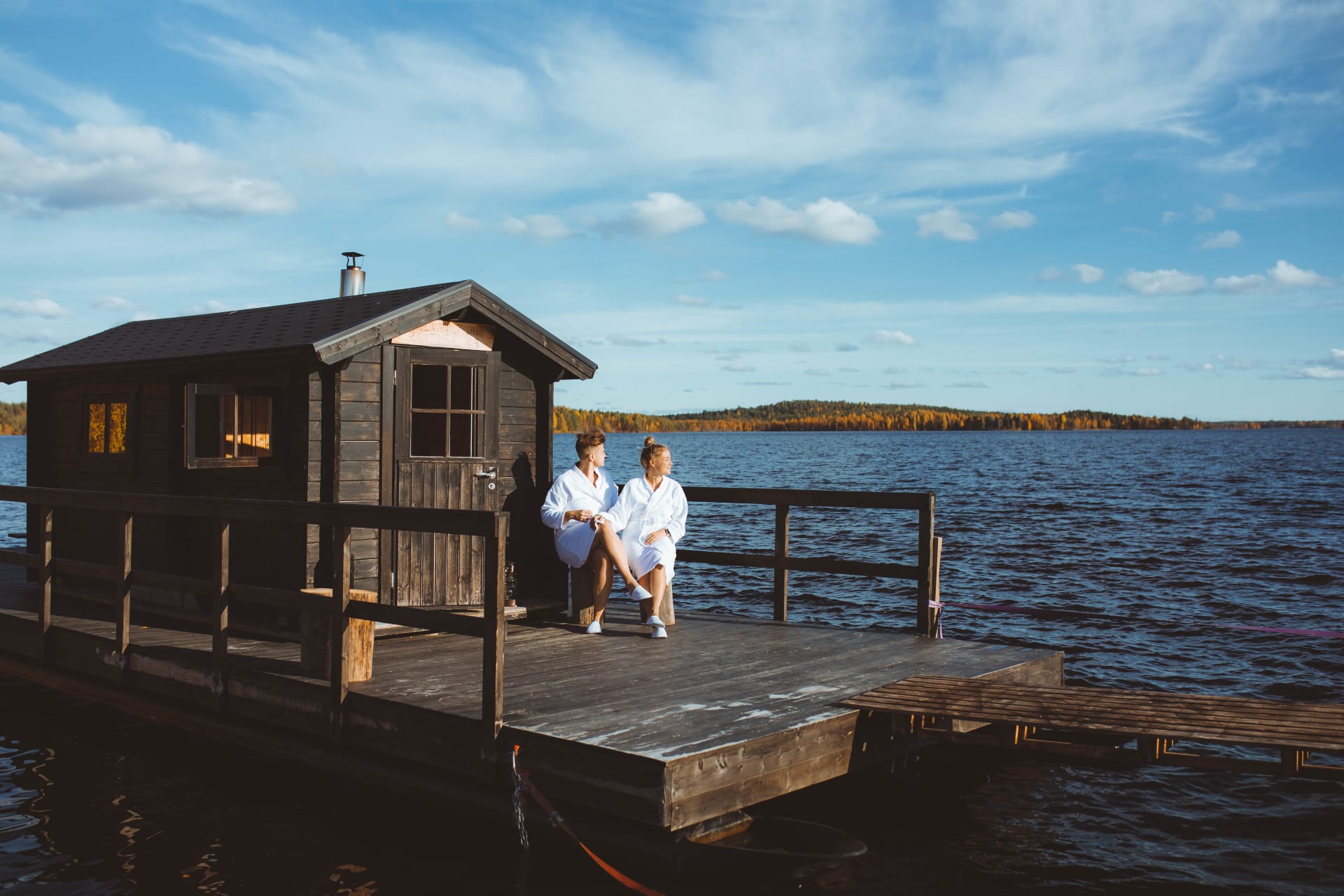 Two people outside Apukka Resort Floating Sauna.