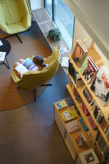 A person sitting on the chair and readind a book in the museum shop.