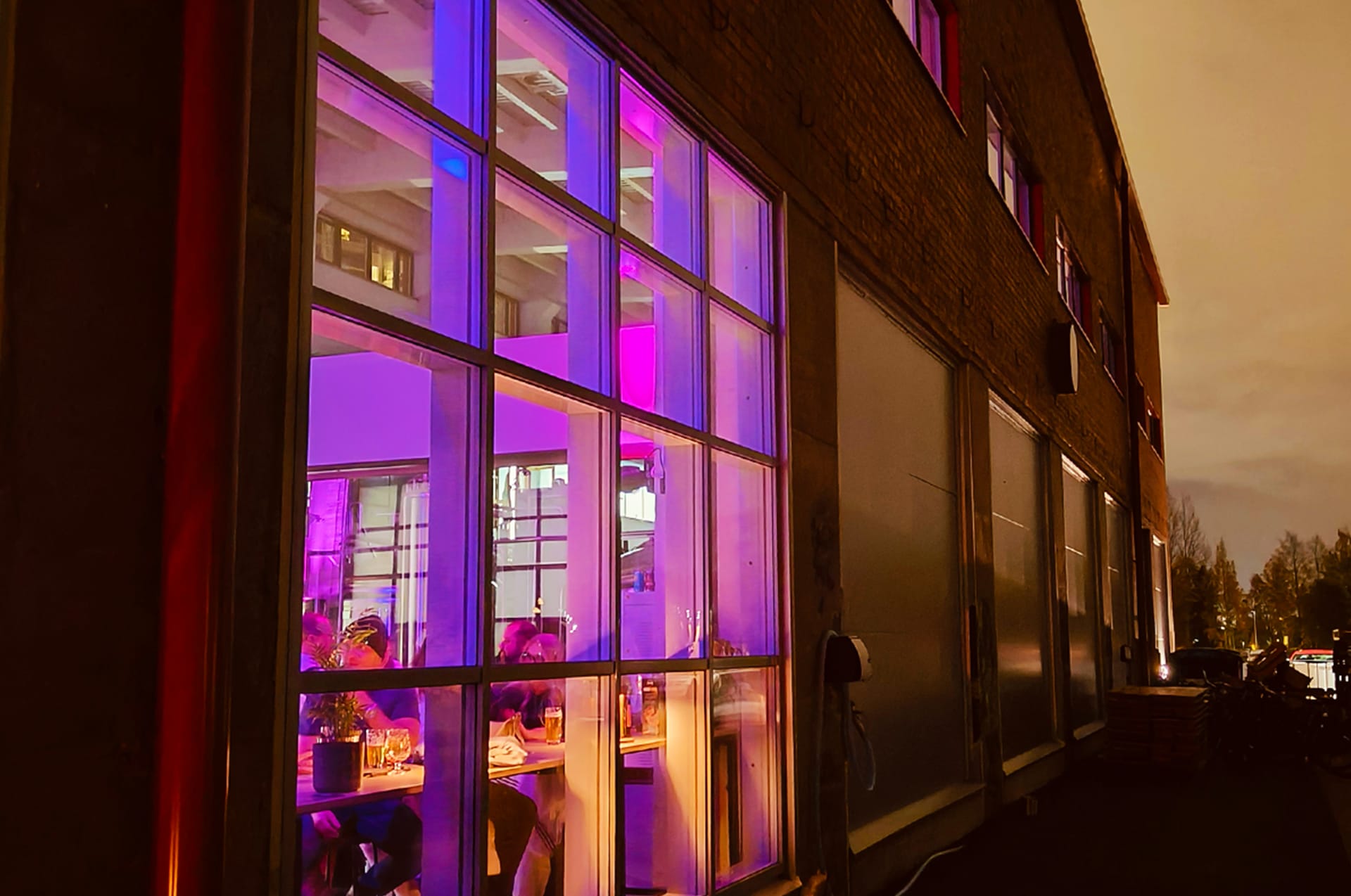 The historic Varikko brewery building glowing with purple lights during a Nordic evening