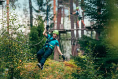 Nainen liukuu vaijeria pitkin Seikkailupuistossa.