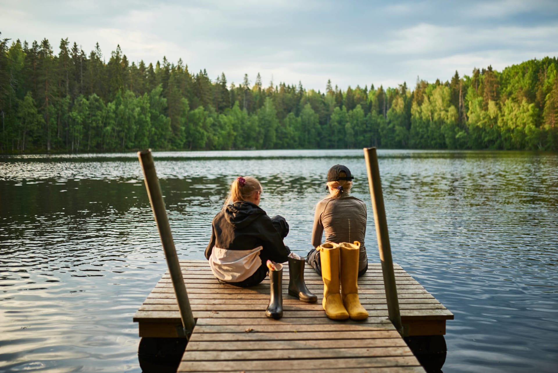 Kaksi lasta istuu laiturilla Ruutanajärven rannalla katsellen järvelle.
