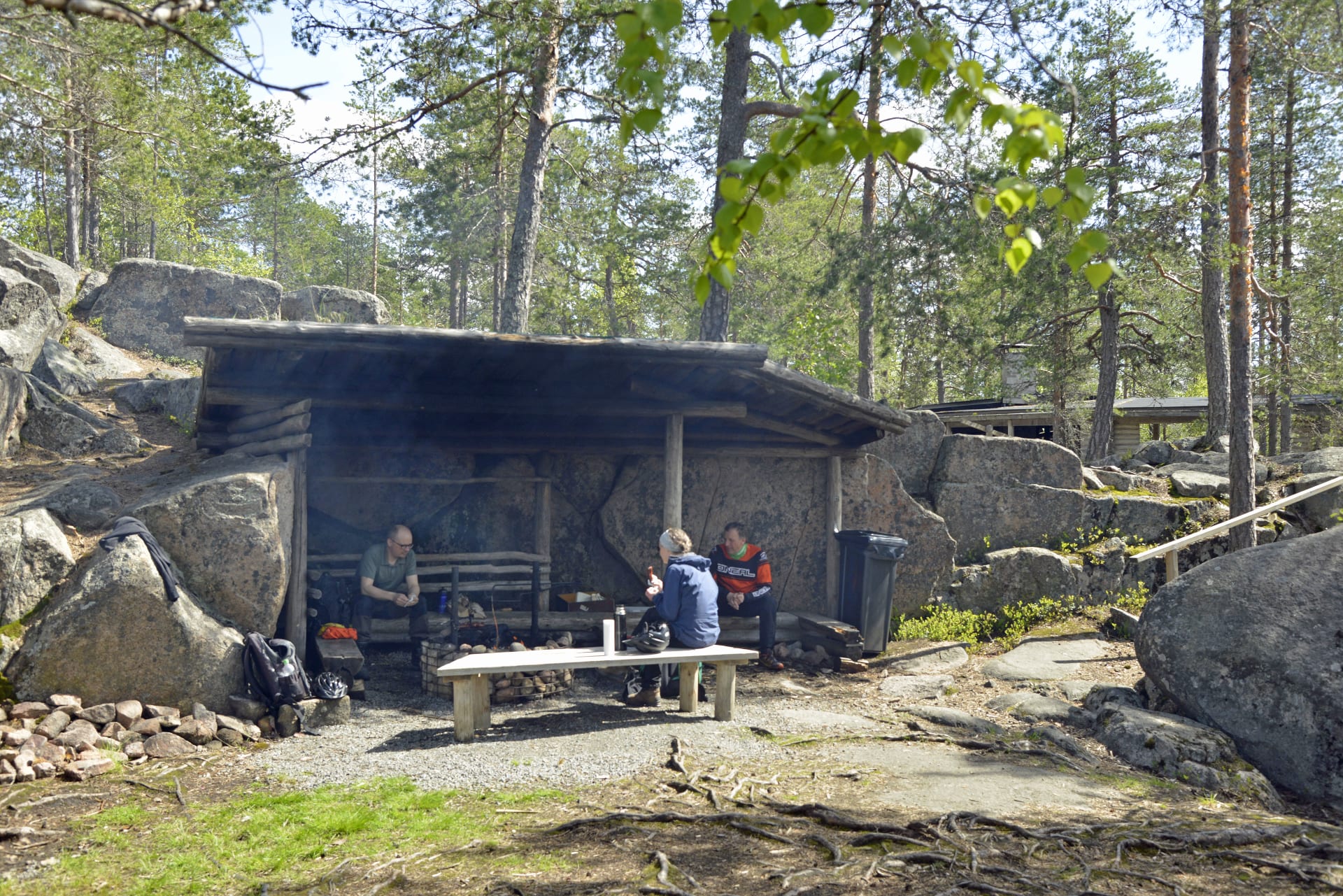 Hikers eating packed lunch in the rocky lean-to shelter of Käskyvuori