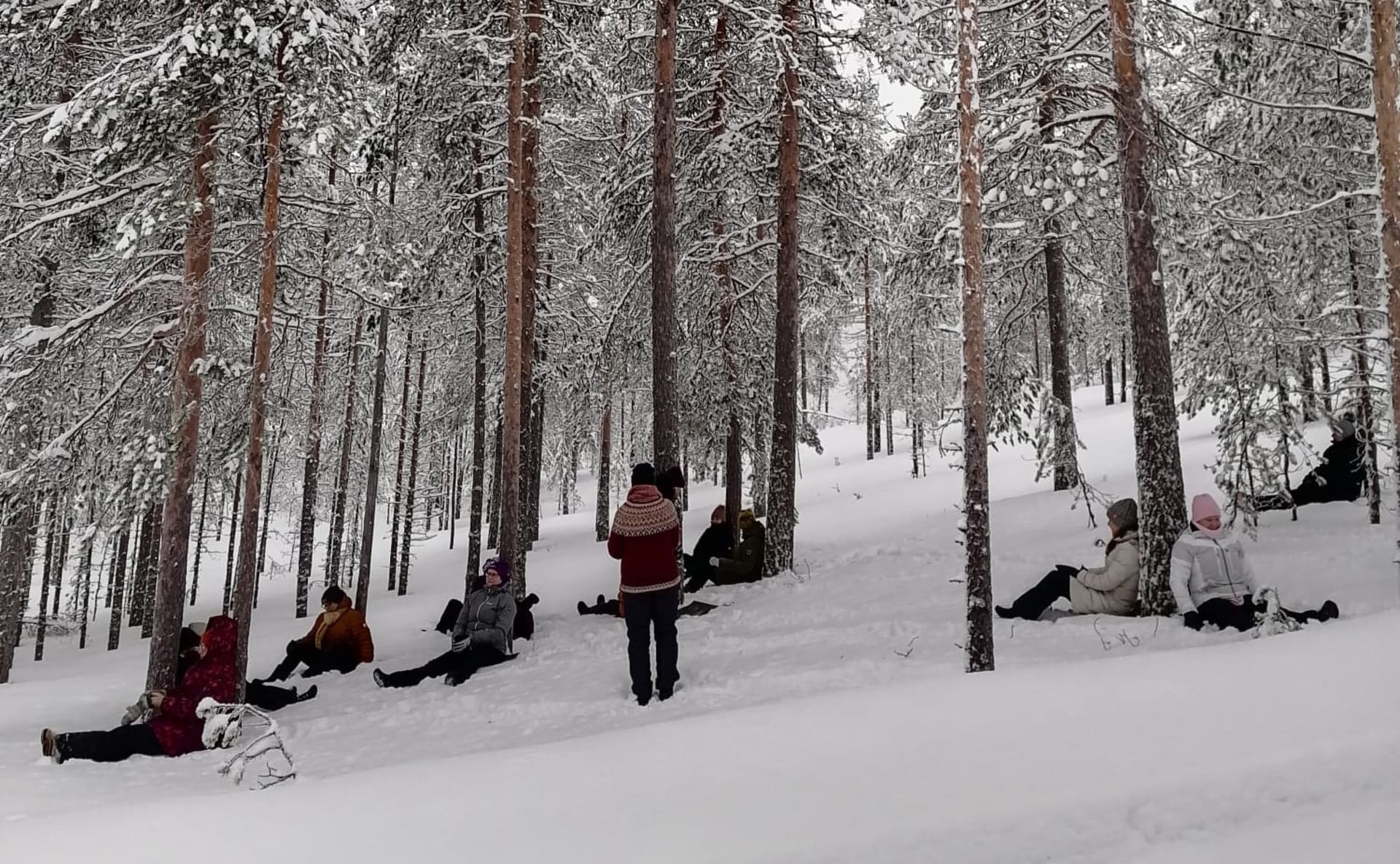 Ihmisiä pötköttämässä talvisessa metsässä.