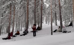 Ihmisiä pötköttämässä talvisessa metsässä.