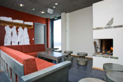 A couch, table, fireplace and rack with towels and bathrobes.