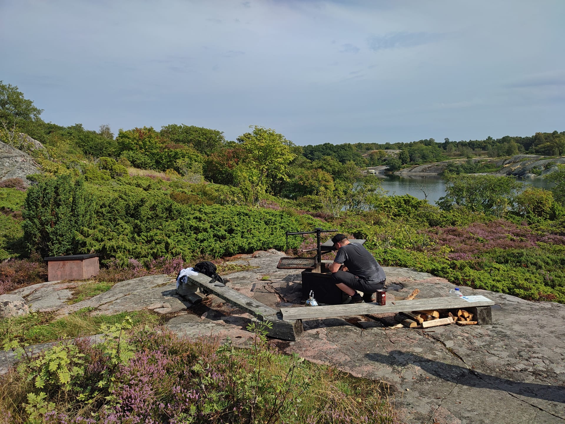 Kalliolla on nuotiokehä, jonka äärellä mies selkä päin kameraa sytyttää nuotiota. Kalliolla on matalaa kasvillisuutta.There is a campfire ring on the rock, next to which a man with his back to the camera lights a campfire.  Kalliolla on nuotiokehä, jonka äärellä mies selkä päin kameraa sytyttää nuotiota. Kalliolla on matalaa kasvillisuutta.There is a campfire ring on the rock, next to which a man with his back to the camera lights a campfire.