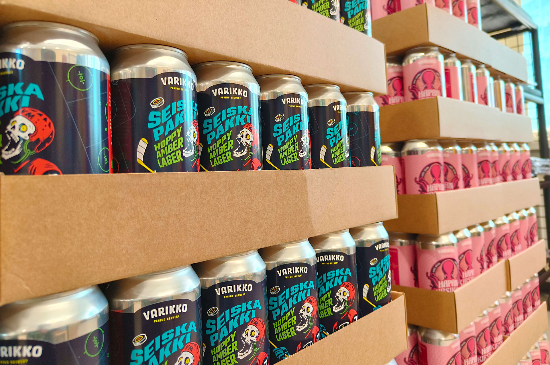 Stacked cartons filled with various craft beer cans in the brewery's industrial-style shop