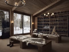 A warm wooden interior with benches covered in sheepskins, shelves of winter helmets and boots, and large windows looking out onto a snowy forest at Jänkä Resort.