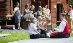 Many museum visitors. In the foreground, a museum employee dressed in traditional costume.