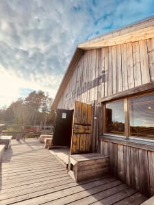 The weathered wooden facade of Cafe Laituri basks in the soft sunlight, inviting visitors into its cozy embrace by the water's edge.