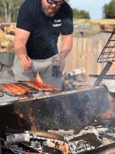 A chef at Cafe Laituri attentively grills salmon, the focus and care in the preparation hinting at a delicious culinary experience to come.