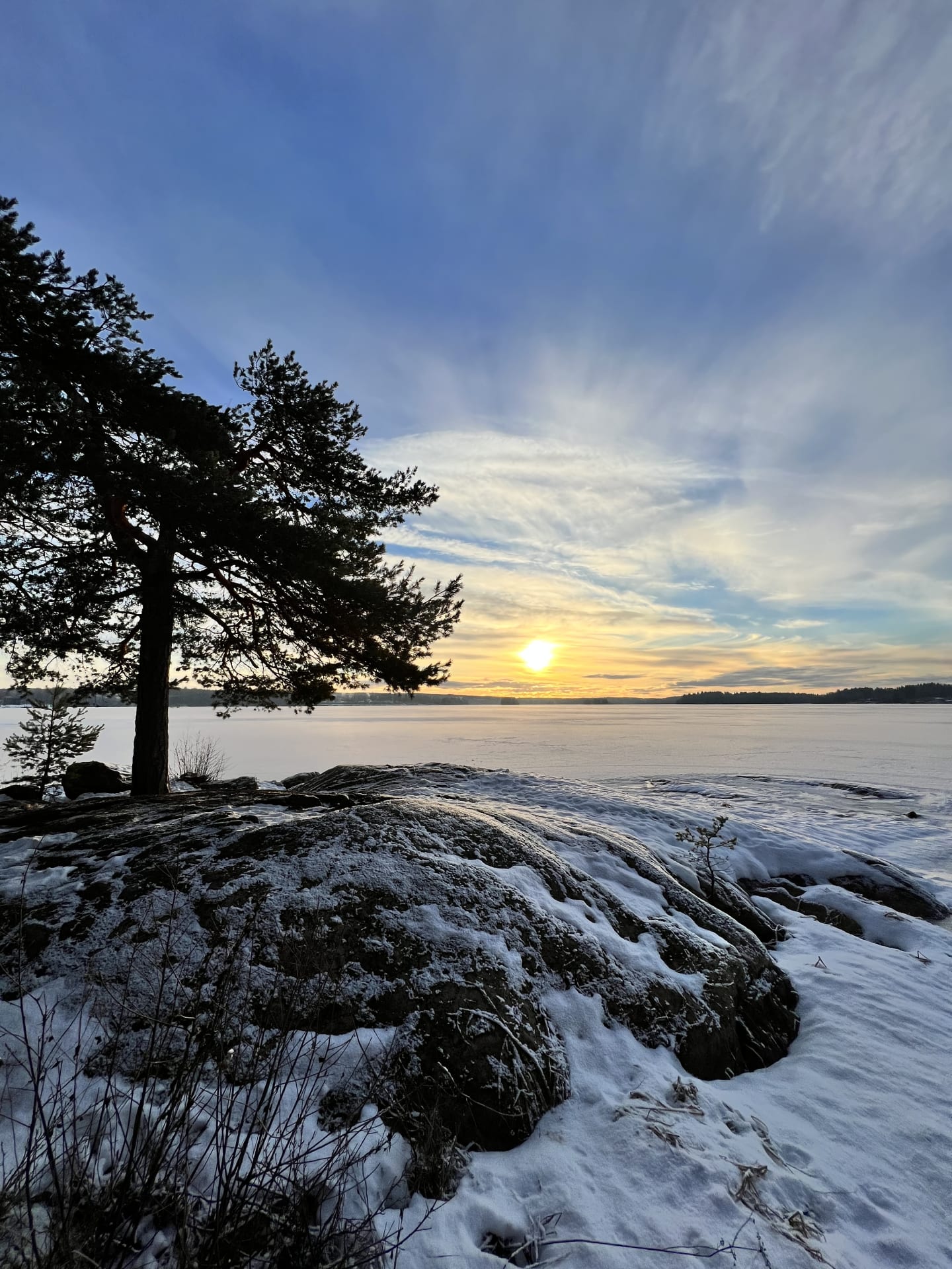 Talvinen auringonlasku järven rannalla