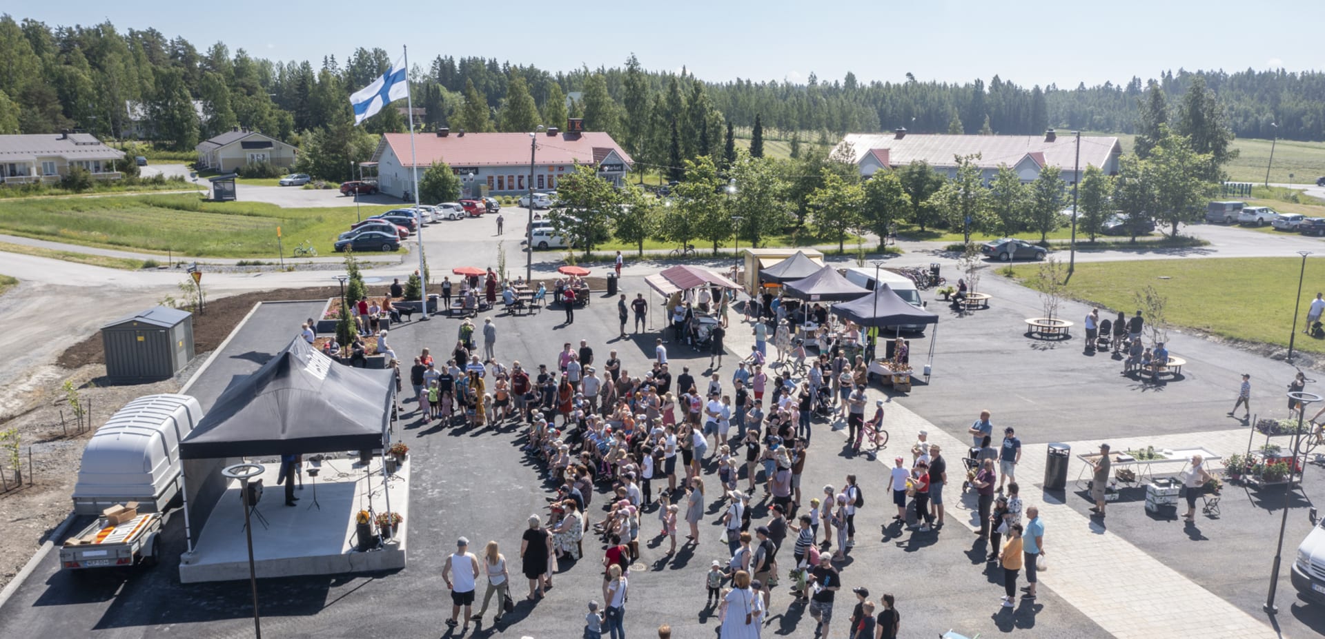 Ilmakuva Vesilahden Kirkonkylän torista, jossa seisoskelee runsaasti väkeä. - ©
