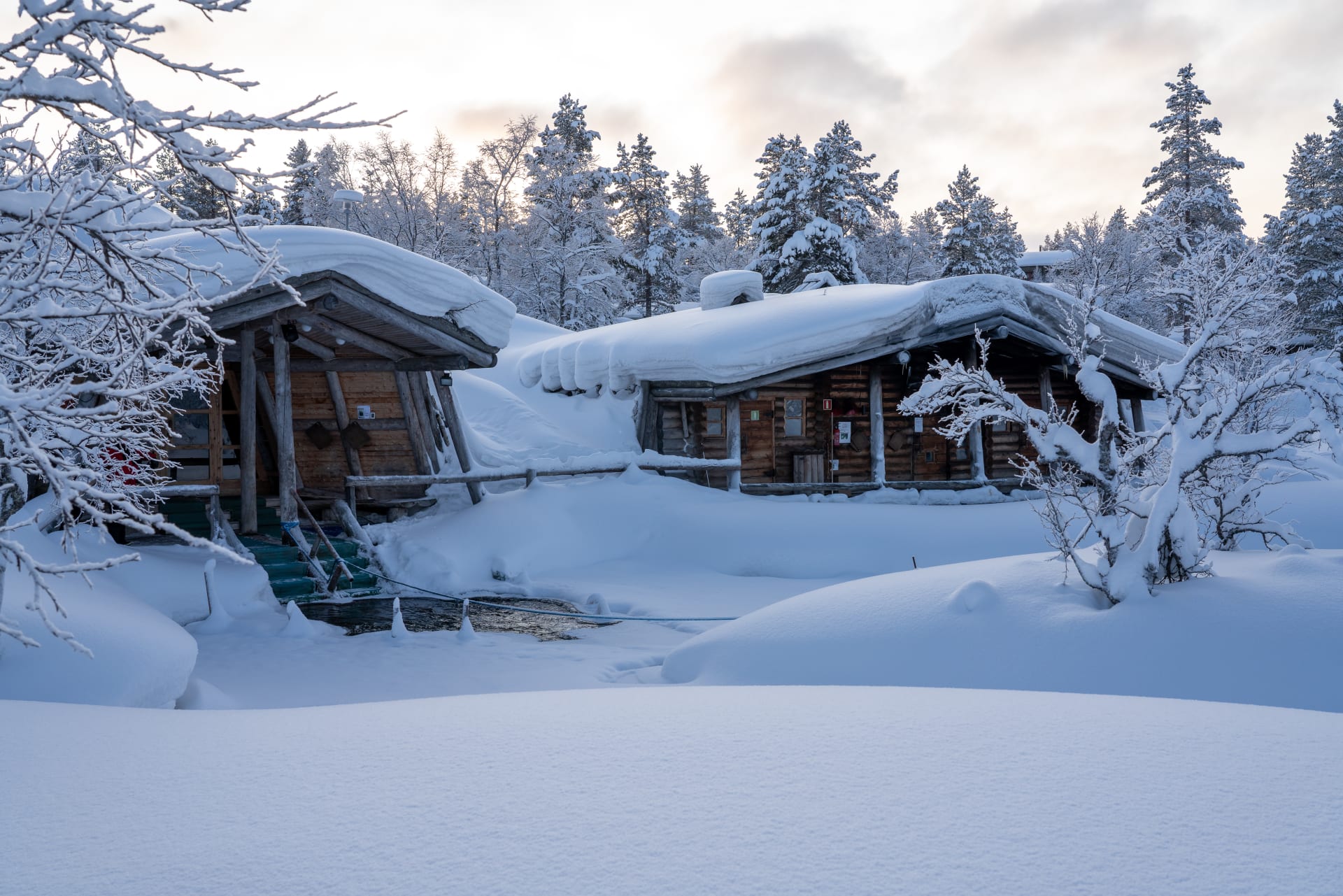 Kuurakaltio savusauna ja Kiilopuron avanto ulkopäin talvella. 