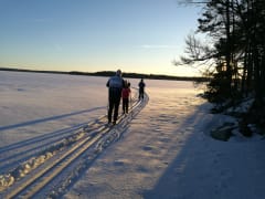 Perhe hiihtää Korpijärven jäälle ajetuilla laduilla. The family skis on the ice on skitracks of Korpijärvi.