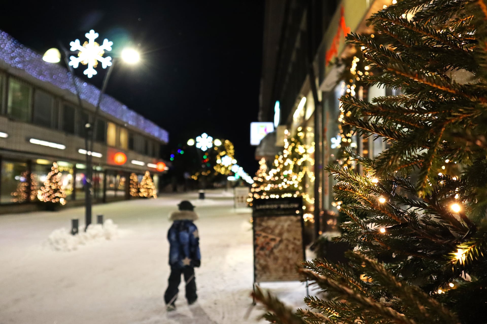 A boy on a pedestrian street at Christmas time.