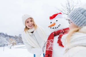 The woman smiles at the cheerful snowman.