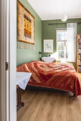 Sänky ja kirjahylly vihreäseinäisessä huoneessa.