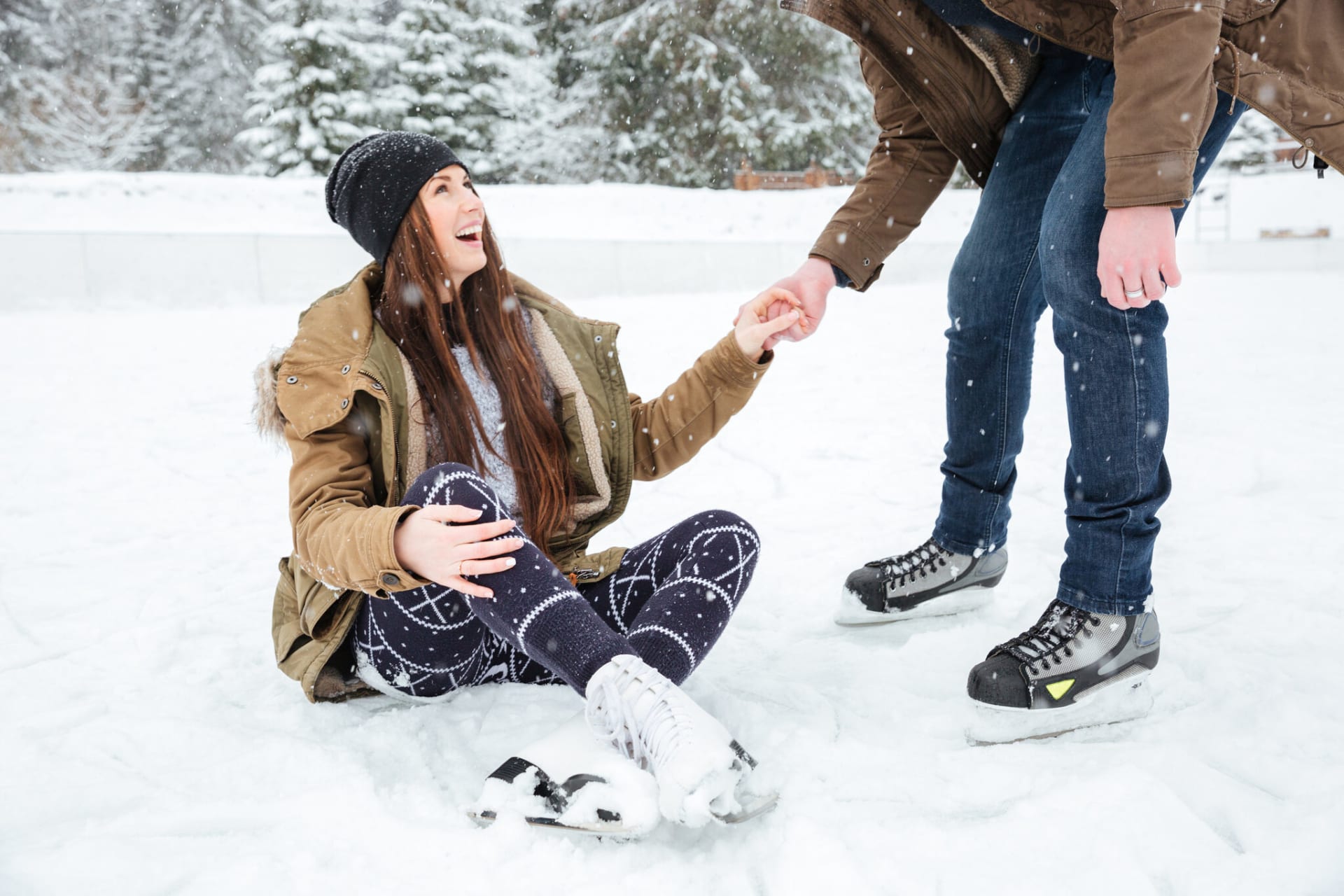 The man helps the woman to get up on her skates.