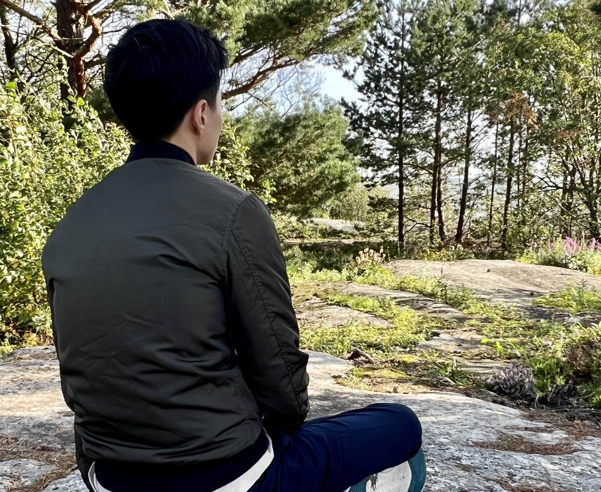 Mies istuu kalliolla metsäkylvyssä