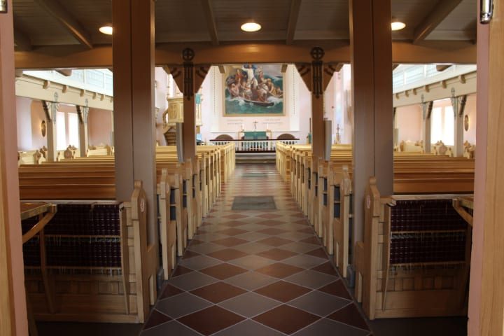 Aisle between rows of benches in The Church of the Holy Trinity in Raahe