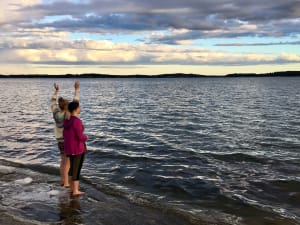 Girls are looking at the sea and waving to the passing ships.