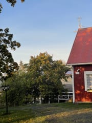 Vanha punainen rakennus ja pihassa puita ja vanha aitta